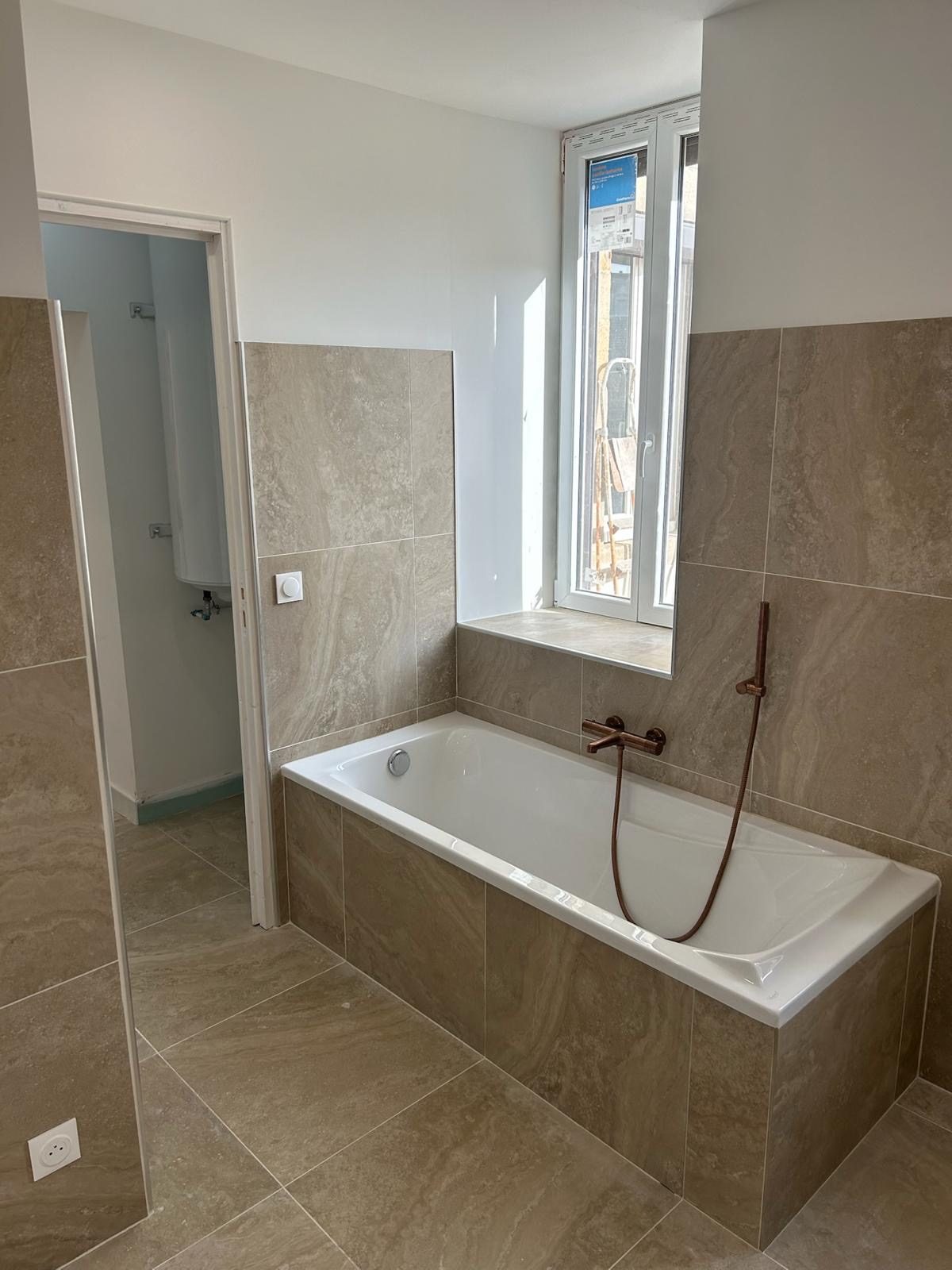 Baignoire encastrée sous la fenêtre, tablette carrelée dans la continuité