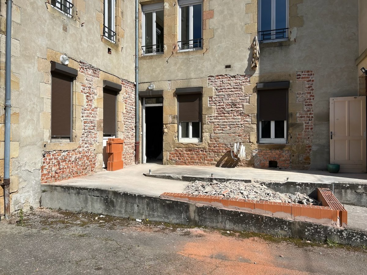 La façade et la cour avant travaux : enduit dégradé, dalle à reprendre, gravats.