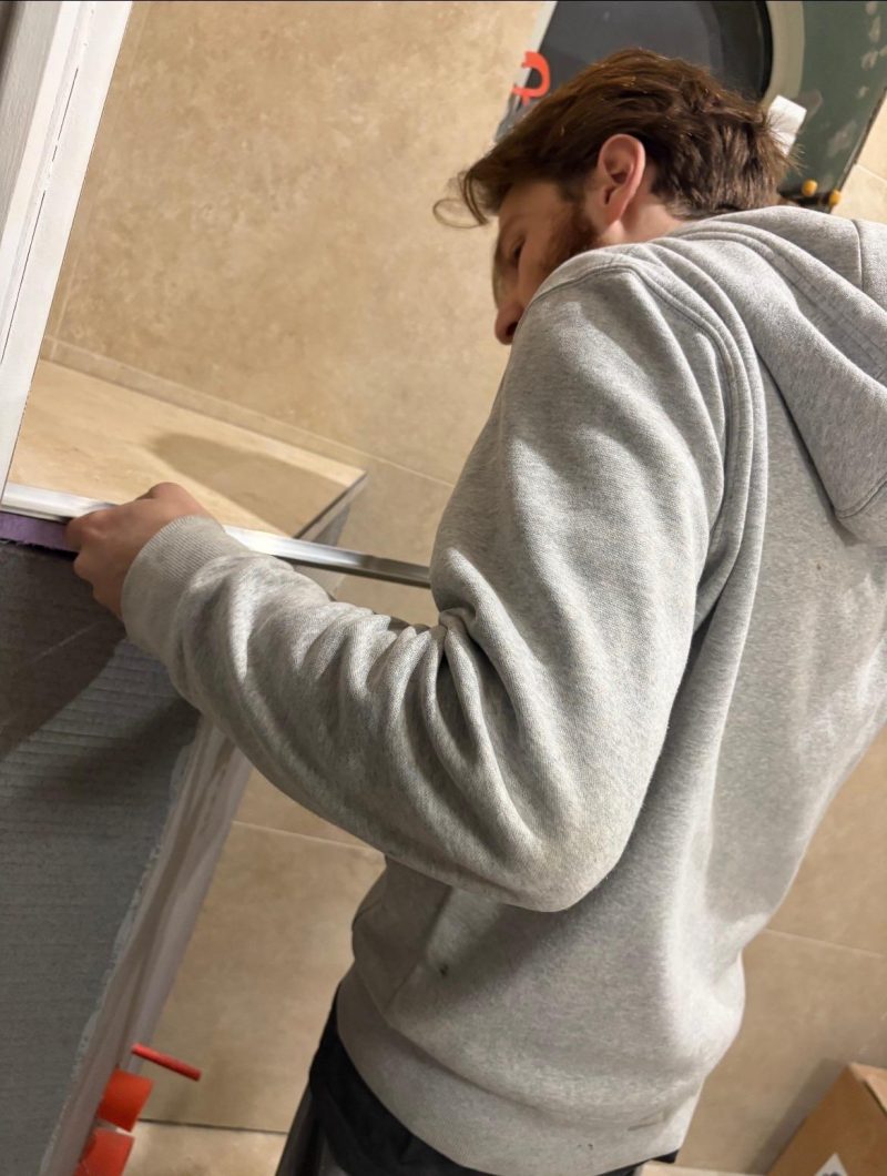 Pose d’une baguette de finition sur l’habillage carrelé