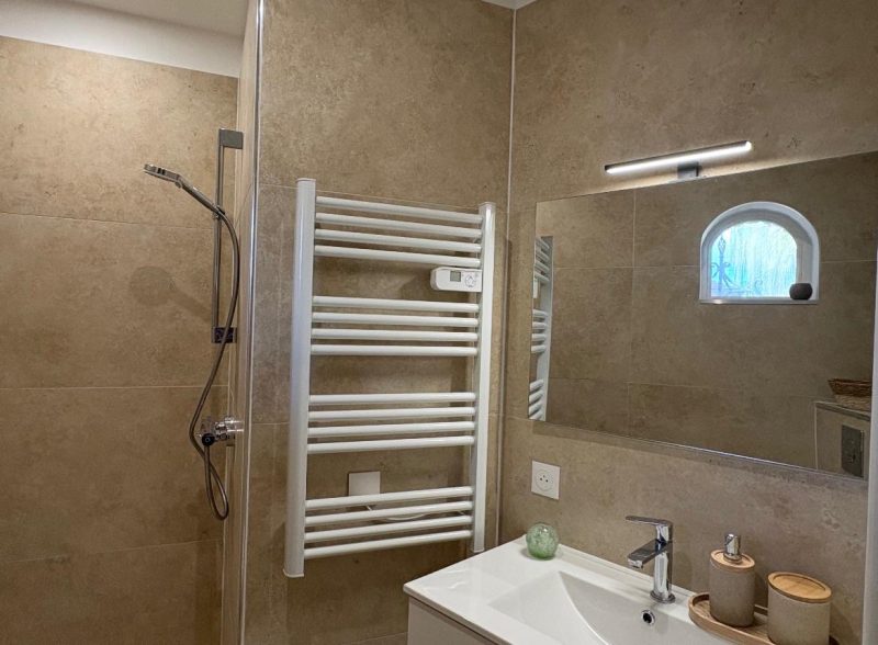 Salle d’eau terminée : douche, sèche-serviettes, meuble vasque et miroir