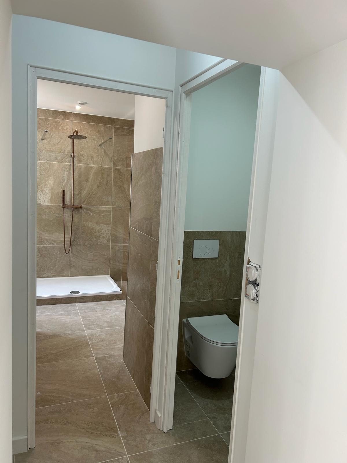 La salle de bains neuve vue depuis le couloir, dont les carreaux de ciment d’origine ont été conservés
